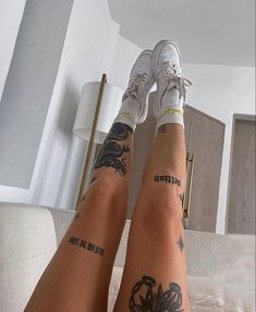 two people with tattoos on their legs sitting on a bed