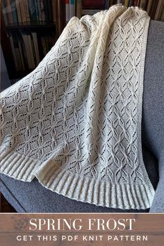 a white knitted blanket sitting on top of a gray couch next to bookshelves