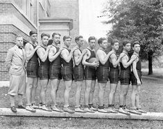 a group of men standing next to each other in front of a building with their hands on their hips