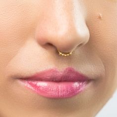 a woman's nose with a gold nose ring on her left side and pink lips