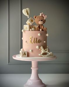 a pink cake with a teddy bear on top