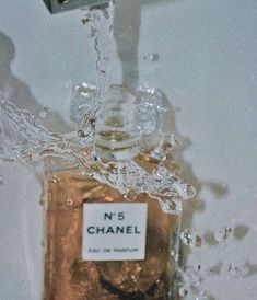 a bottle of chanel no 5 perfume is being poured into the water from a faucet