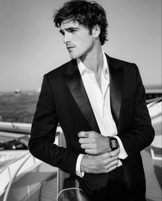 a man in a tuxedo standing on a boat looking off into the distance