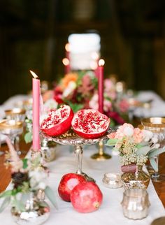 the table is set with candles and pomegranates for an elegant wedding