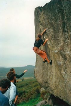 a man climbing up the side of a large rock