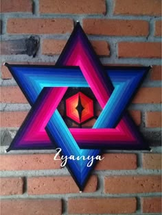 a colorful star hanging on the side of a brick wall with an ornament