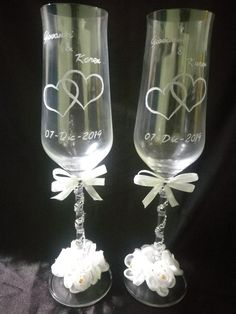 two wine glasses with hearts and flowers on the bottom, one has a bow at the top