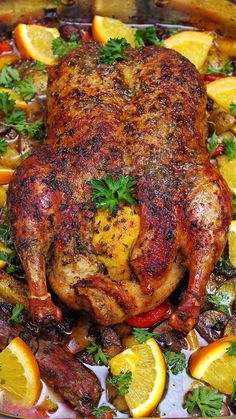 roasted duck in wine with potatoes, peppers and mushrooms on a platter surrounded by oranges