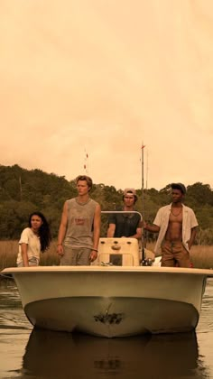 three men and a woman on a small boat in the water with trees in the background