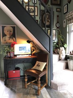 a chair under a staircase next to a desk with a computer on top of it