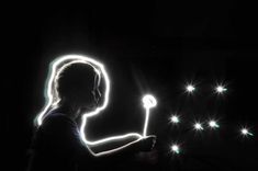 a person holding a light up stick in the dark