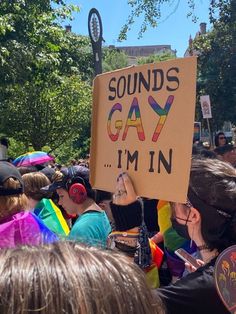 a group of people standing around each other holding up signs that say sounds gay i'm in