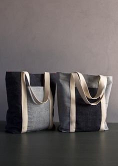 two canvas bags sitting on top of a table next to each other, one with a white and black stripe