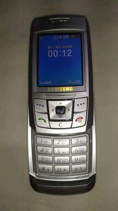 an old samsung cell phone sitting on top of a white table with the time displayed