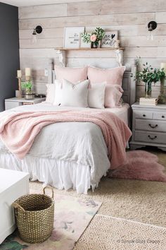 a white bed with pink blankets and pillows