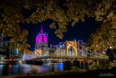 the city lights shine brightly in the night sky over water and bridge with buildings on both sides