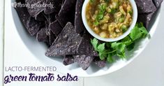 a white plate topped with tortilla chips next to a bowl of salsa and guacamole