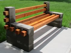 a wooden bench sitting on top of a cement slab in the grass next to a field