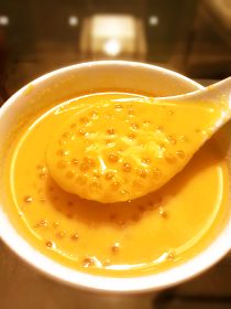 a white bowl filled with yellow liquid and a spoon