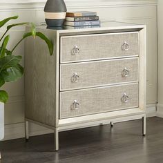 a white chest of drawers sitting next to a potted plant