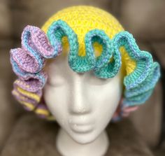 a white mannequin head with two crocheted hats on it's sides