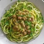 a white bowl filled with zucchini and meat sauce