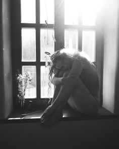 a woman sitting on top of a window sill