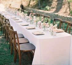 a long table is set up with flowers and place settings for the guests to sit at