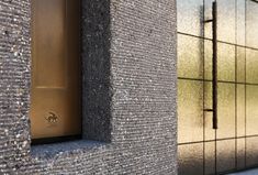 a close up of a metal door on a brick wall near another building with glass windows