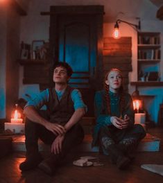 two people sitting on the floor in a room with candles around them and one person looking up