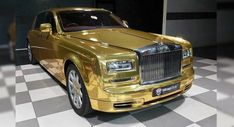 a gold colored rolls royce parked on a checkered floor