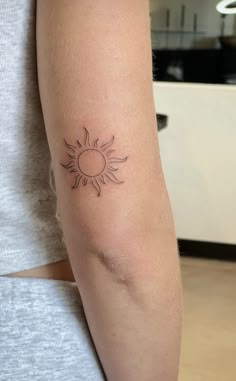 a woman's arm with a tattoo that has a small sun on the side