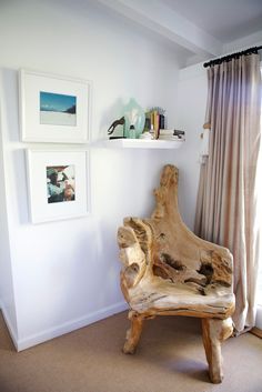 a wooden chair sitting in front of a window next to a wall with pictures on it