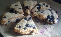 blueberry scones cut in half on top of a piece of paper with one slice missing