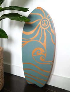 a surfboard sitting on top of a wooden floor next to a potted plant