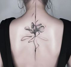 the back of a woman's neck with a flower tattoo on her left side