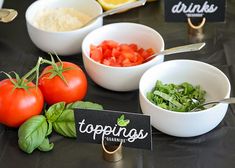 several different types of food are displayed on a table with signs and utensils