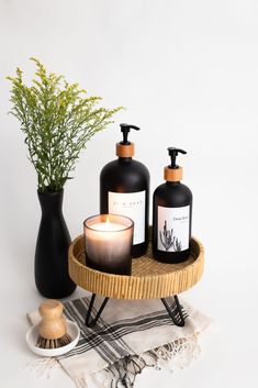 two bottles with soaps and candles on a tray next to a potted plant