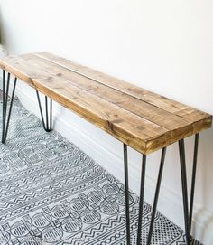 a wooden bench sitting on top of a white floor next to a black and white rug