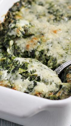 spinach and cheese casserole in a white dish on a blue tablecloth