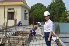 a woman wearing a hard hat standing on top of a construction site with other people