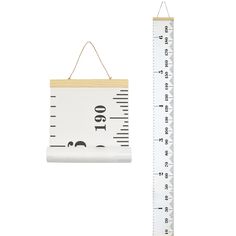 a wooden ruler hanging on a wall next to a white and black measuring board with the word cut out