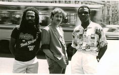 three men standing next to each other in front of a bus