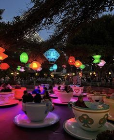 teacups and saucers lit up at night with paper lanterns in the background