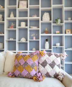 a couch with two pillows on it in front of a book shelf filled with books