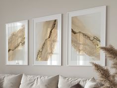 three paintings hang on the wall above a couch