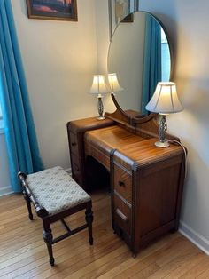 a wooden desk with a mirror on top of it next to a chair and lamp