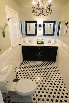 a bathroom with black and white tile flooring, two sinks, toilet and mirror