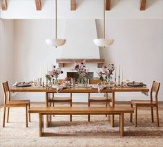 a dining room table set with flowers, candles and place settings for four people to sit at