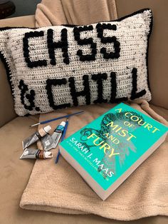 a crocheted pillow with scissors and a book on the couch next to it